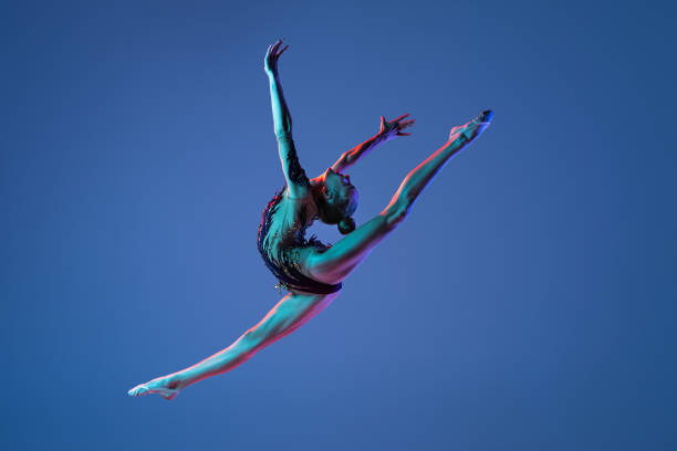 Poster. Contemporary art collage. Young athlete woman, professional gymnast performing extreme tricks in neon light. Concept of sport, active and healthy lifestyle, tournament. Retro effect, art style