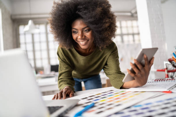 istock Smiling afro female designer in a creative office, working on laptop 1347632963