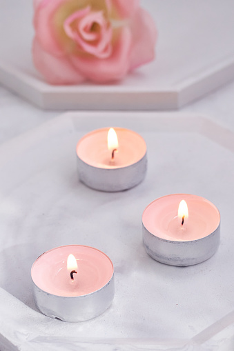 Beautiful composition of pink candles and rose on white stone stands.Romantic atmosphere for lovers.