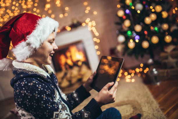 istock Cute little boy playing on tablet in front of a christmas tree 1347638184