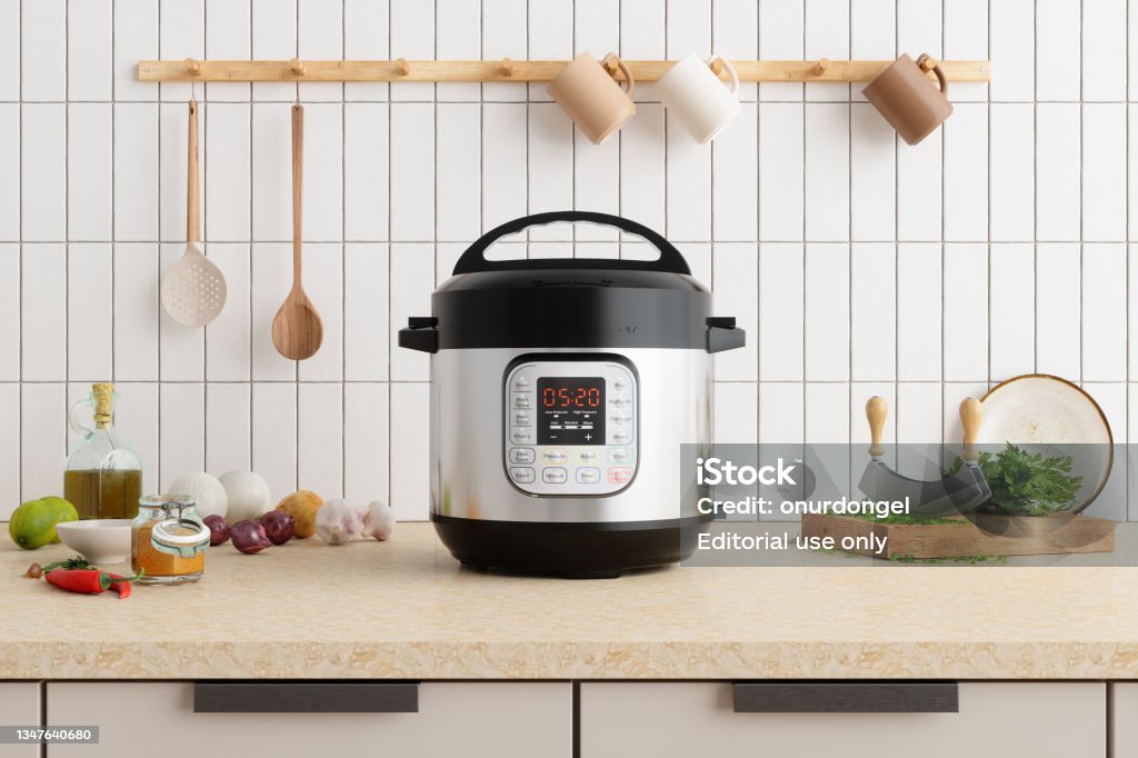 Multi Cooker On Kitchen Counter With Onions, Garlic, Cooking Oil And Cutting Board Crock Pot Stock Photo