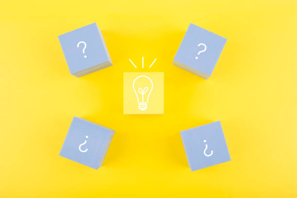 istock Creativity and fresh ideas concept. Light bulb and question signs drawn on toy cubes on yellow background 1347643490