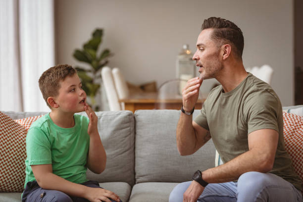 istock Caucasian father and son communicating using sign language while sitting on the couch at home 1347645003