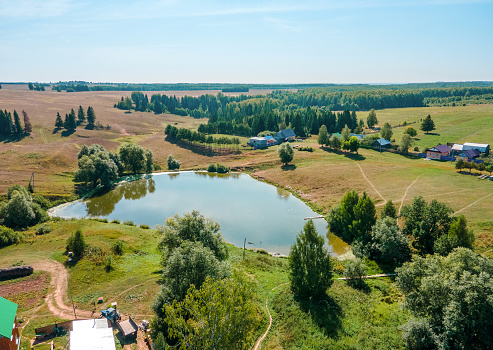 Russian village at a flat terrain among agricultural fields. A sunny summer day at Mari Republic, Volga Region, Russia. A bird's eye view