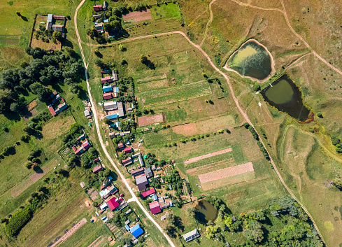 Russian village at a flat terrain among agricultural fields. A sunny summer day at Mari Republic, Volga Region, Russia. A bird's eye view