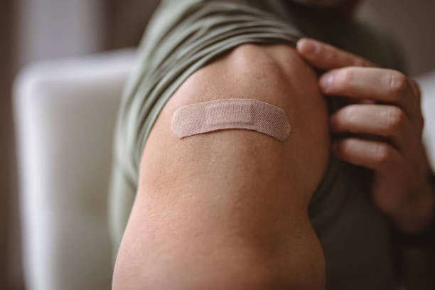 istock Mid section of caucasian man showing his vaccinated shoulder at home 1347649044