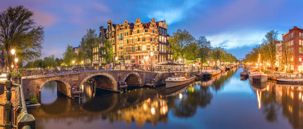 Panoramic view of the historic city center of Amsterdam. Traditional houses and bridges of Amsterdam town. A romantic evening and a bright reflection of houses in the water. Amsterdam. Panoramic view of the historic city center of Amsterdam. Traditional houses and bridges of Amsterdam town. A romantic evening and a bright reflection of houses in the water. European travel to the historic city. Europe, Netherlands, Holland, Amsterdam. amsterdam stock pictures, royalty-free photos & images