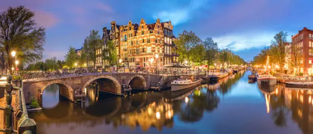 Photo of Panoramic view of the historic city center of Amsterdam. Traditional houses and bridges of Amsterdam town. A romantic evening and a bright reflection of houses in the water.