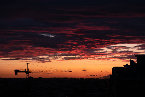 istock City buildings and construction crane silhouettes, dramatic Colorful sunset 1347651892