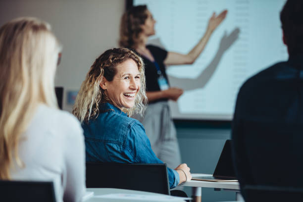 businesswoman smiling during a presentation - yetişkin eğitimi stok fotoğraflar ve resimler