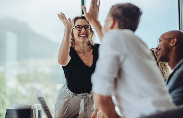 geschäftsfrau, die einem kollegen in einem meeting ein high five gibt - high five stock-fotos und bilder