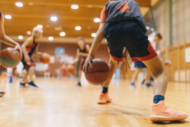 Young Basketball Player on Practice Session. Youth Basketball Team Bouncing Balls on Sports Court. Group of Kids Training Basketball Together Young Basketball Player on Practice Session. Youth Basketball Team Bouncing Balls on Sports Court. Group of Kids Training Basketball Together sports activity stock pictures, royalty-free photos & images