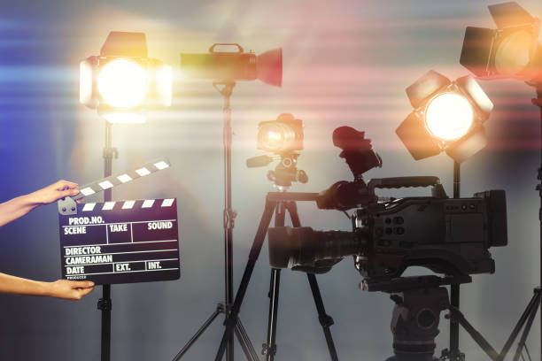 istock Woman with clapperboard near modern professional video camera in studio, closeup 1347654791