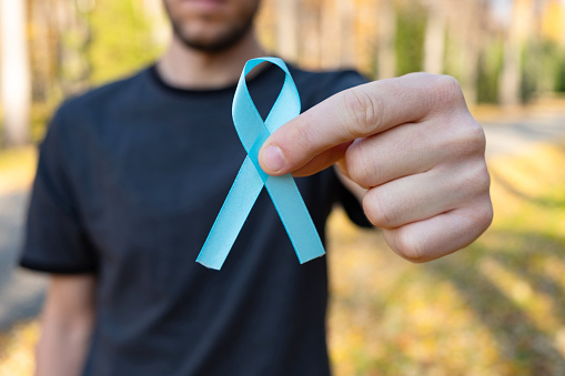 Man with light blue awareness ribbon. Close up