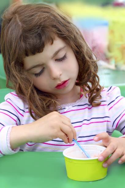 istock brunette little girl eating ice cream 1347656201