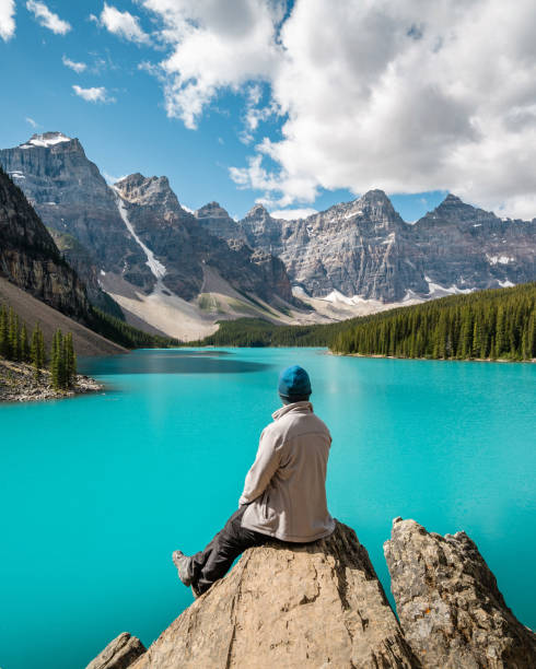 Hiker Looking at View at Moraine Lake, Banff National Park, Alberta, Canada Hiker looking at view at Moraine Lake during summer in Banff National Park, Alberta, Canada. rocky mountains banff alberta mountain stock pictures, royalty-free photos & images