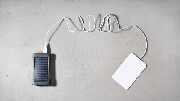 istock Portable heater is connected by wire with USB to power bank with solar panel on gray background 1347668395