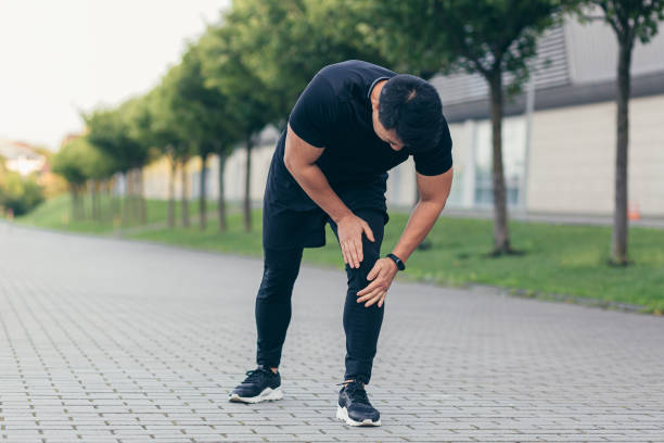 azjata trzymający ból kolana po bieganiu i sprawności, silny ból nóg - men jogging running sports training zdjęcia i obrazy z banku zdjęć