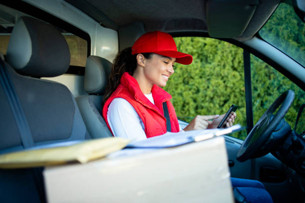entregador feminino verificando encomendas em tablet digital antes da entrega. - driving van driver delivering - fotografias e filmes do acervo