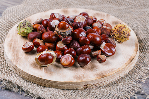 Edible chestnut kernels lie on a wooden cutting board made of plywood.