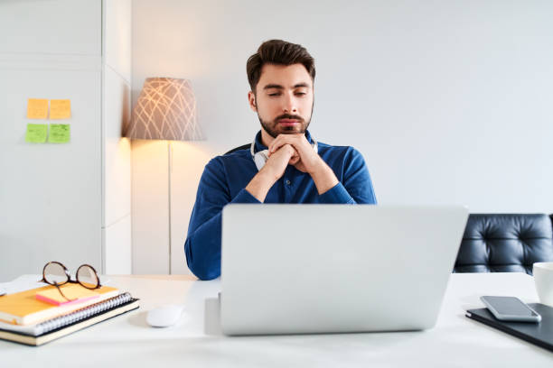 istock Pensive young man looking on laptop working at home 1347677735