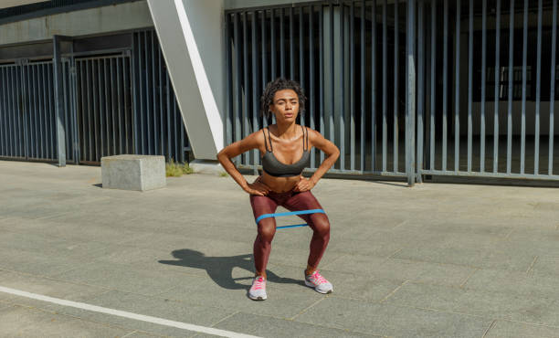 istock Attractive young woman does squats with elastic band and raises hands 1347681562