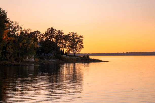 Sunset on the water in Canada Colourful sunset sky with trees and land jutting into the water calm water stock pictures, royalty-free photos & images