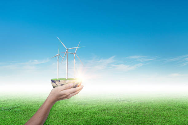 istock Hands holding wind turbine on grass field against blue sky background. 1347683883