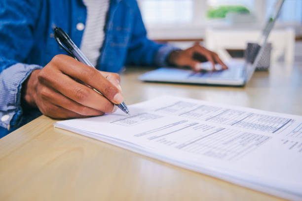 istock Shot of an unrecognisable man using a laptop and going through paperwork at home 1347684095