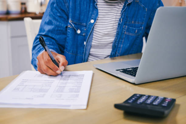 istock Shot of an unrecognisable man using a laptop and going through paperwork at home 1347684096