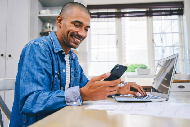 istock Shot of a young man using a laptop and smartphone while working at home 1347684100