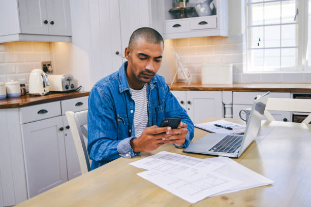 istock Shot of a young man using a laptop and smartphone while working at home 1347684103