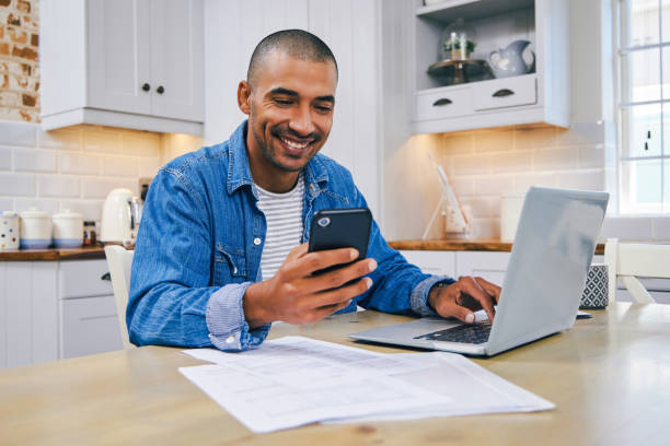 istock Shot of a young man using a laptop and smartphone while working at home 1347684105