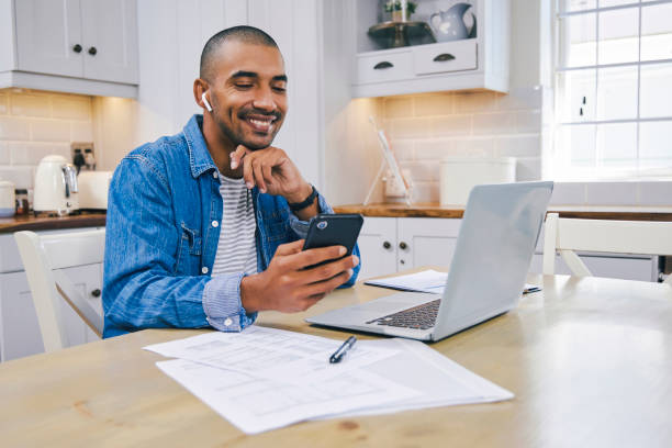 istock Shot of a young man using a laptop and smartphone while working at home 1347684125