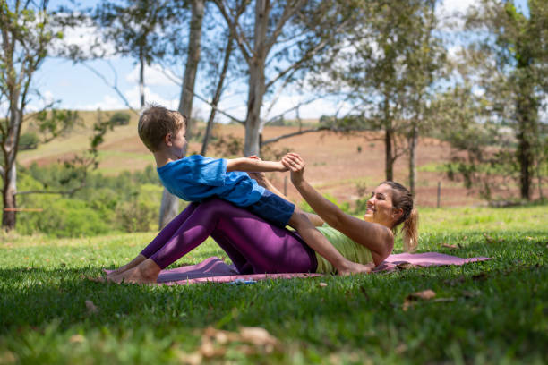 Mother and son practice yoga exercises and stretching outdoors stock photo