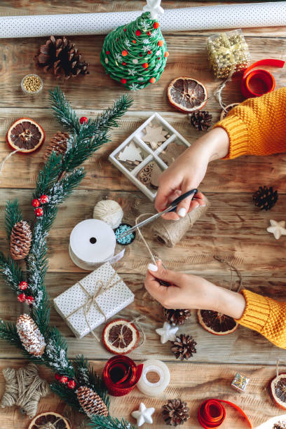 istock Young woman wrapping christmas present on table with new year decorations 1347687969