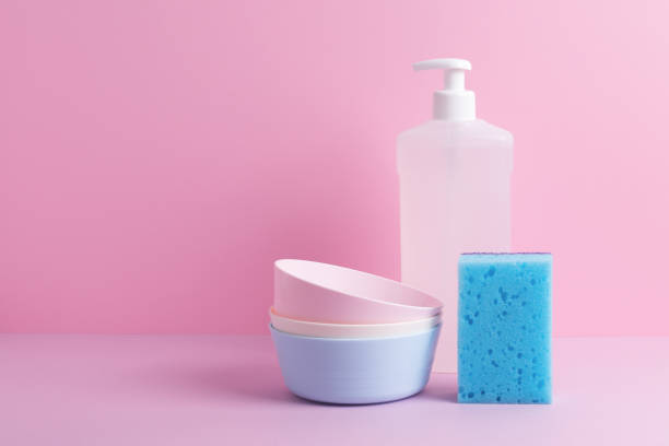 istock Dish wash liquid, clean plates and blue sponge on pink background. 1347690432