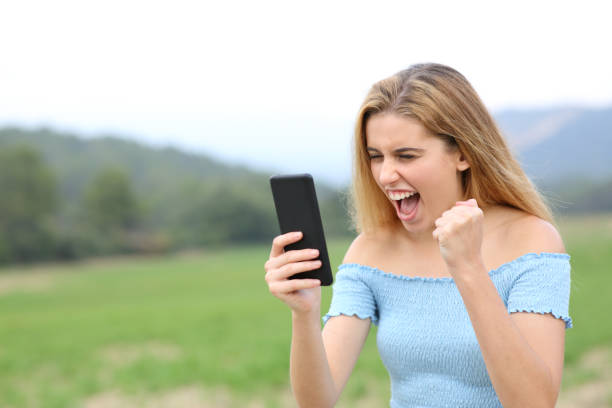 istock Excited teen checking content on smart phone in a field 1347690484