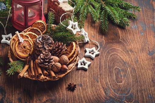 Dry orange, star anise, cinnamon, pine cones and fir tree in rustic plate on wooden table. Homemade medley idea for Christmas mood and aroma. Eco friendly christmas with homemade natural decorations.