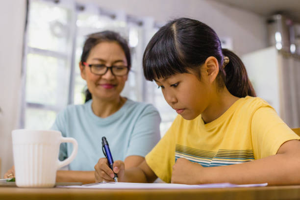 istock Happy Asian mother helping her teenage daughter doing homework or studying and E-learning lesson while sitting in living room 1347691322