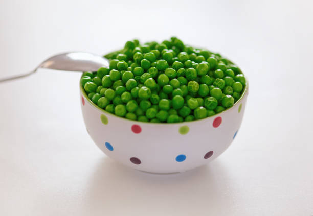 Young boy eating green peas for dinner
