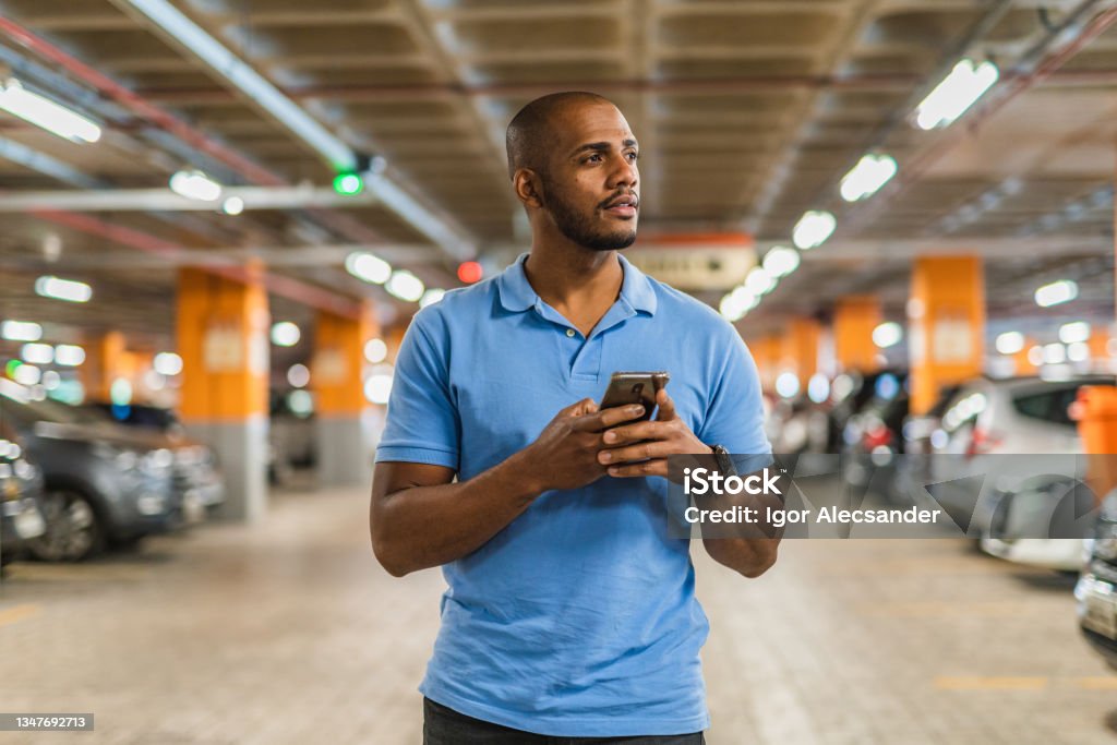Man holding smartphone in parking lot Man holding smartphone in parking lot. Parking Lot Stock Photo