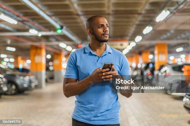 Man Holding Smartphone In Parking Lot Stock Photo - Download Image Now - Parking Lot, Lost, Shopping Mall