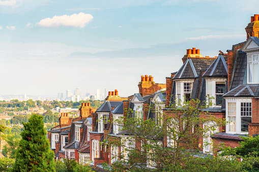 A row of traditional houses on a street in London's Muswell Hill suburb, located to the north of London, with views of the Canary Wharf on the horizon.