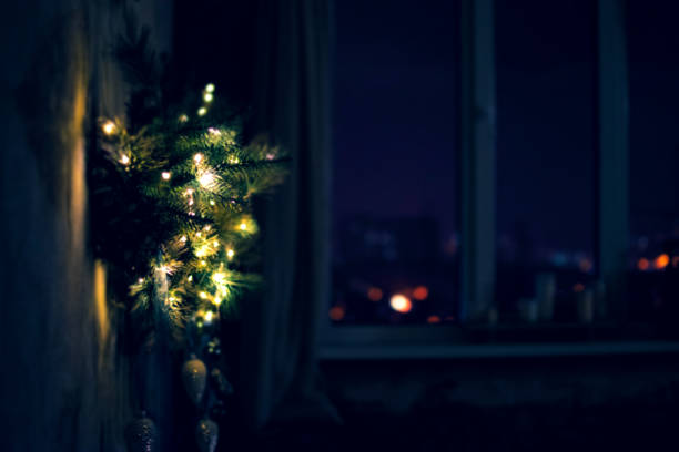 istock Unfocused home interior with window and green New Year tree decorated with lights and Christmas ornaments 1347694159