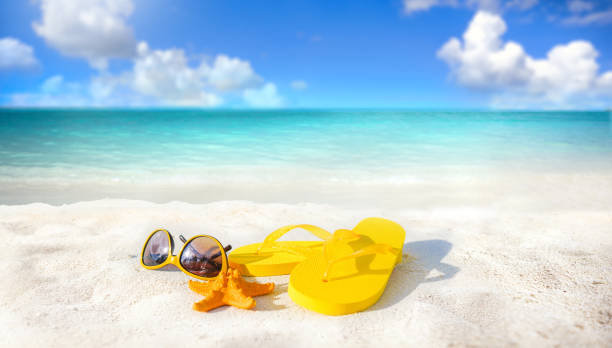 istock Beach accessories - sunglasses, starfish, yellow flip-flops on sandy tropical beach. 1347694507
