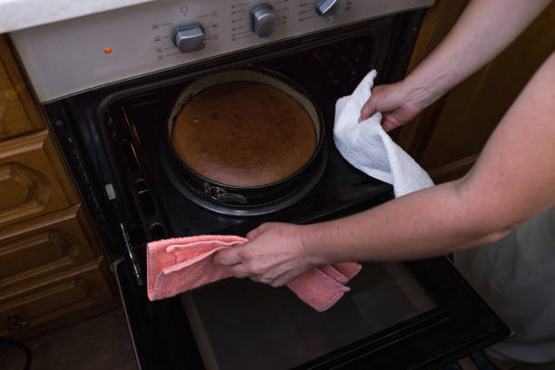 istock A step-by-step process for making a sour cream chocolate cake. Women's hands get the finished cake out of the oven. 1347695360