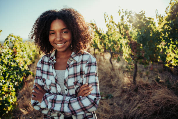 Mixed race female farmer standing with crossed arms smiling standing in beautiful vineyards