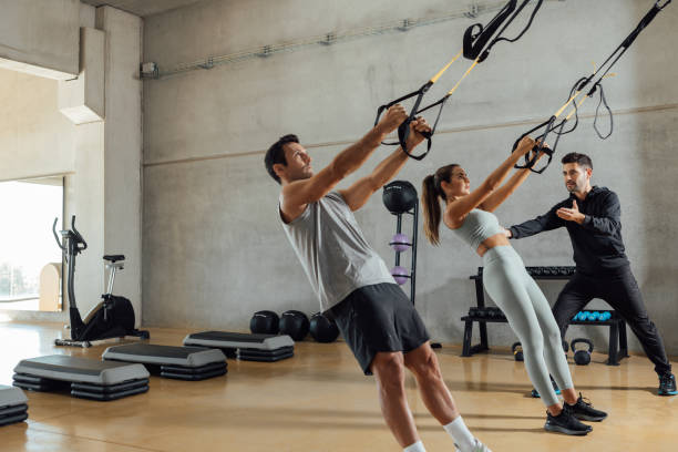 istock Personal trainer helps a couple that work out with elastic resistant strap. 1347698699