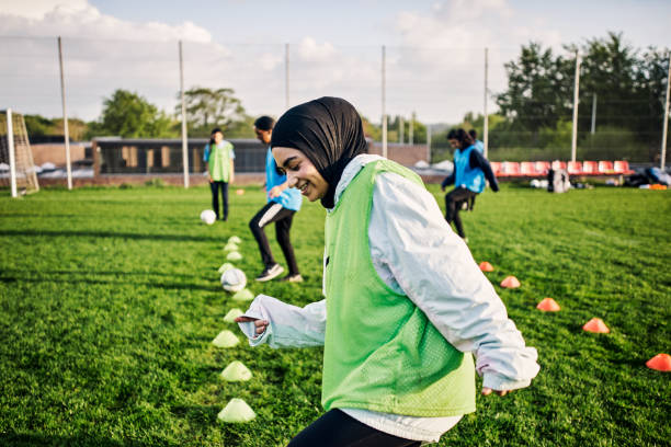 scatto ritagliato di una giovane calciatrice atletica che si allena in campo con le sue compagne di squadra sullo sfondo - hijab foto e immagini stock